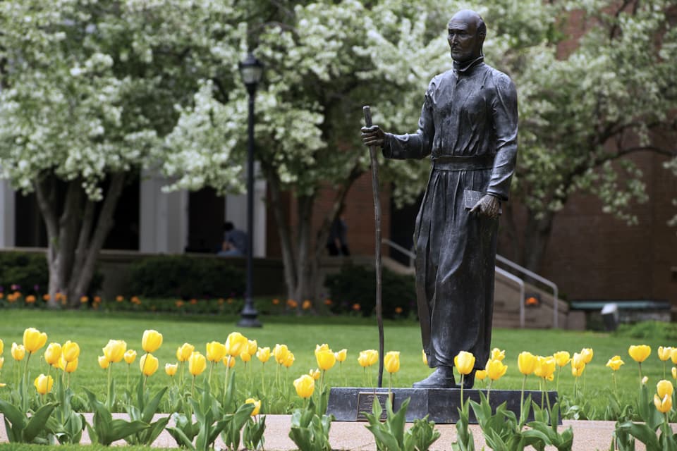 Ignatius statue in the quad surrounded by tulips