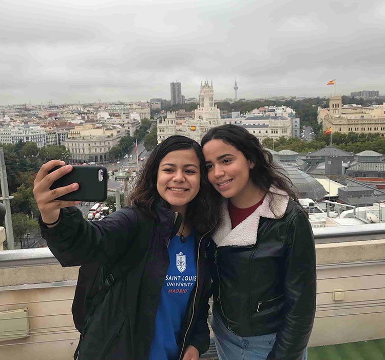two girls take a selfie in Madrid overlooking church in distance